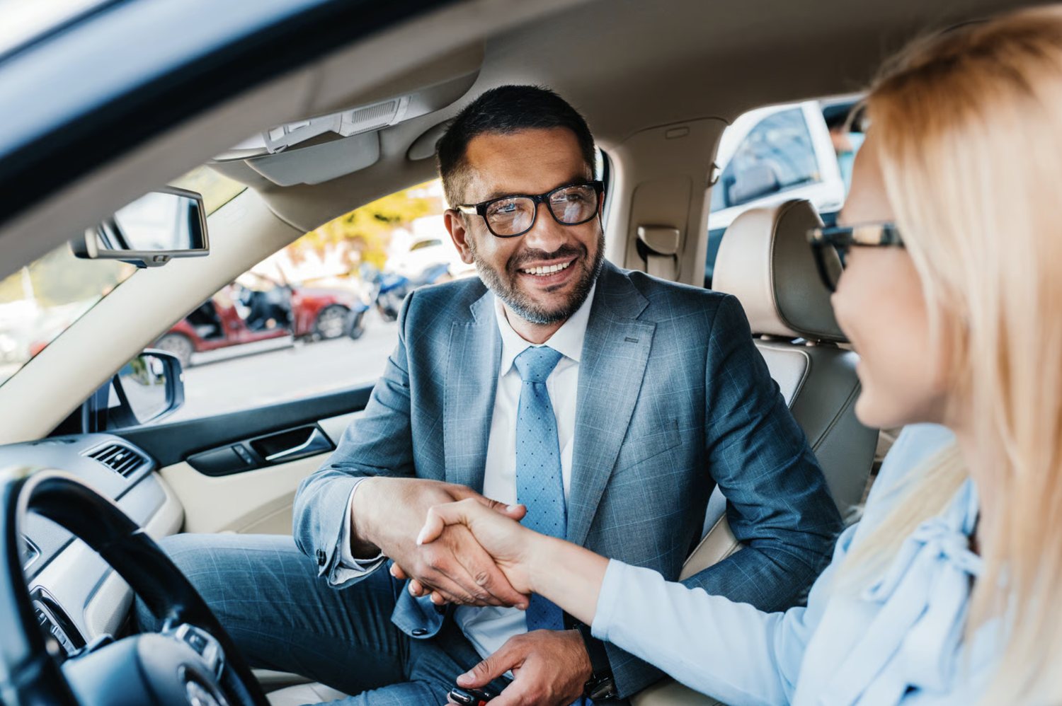 Reel Deal Auto salesperson shaking hands with a customer in their new car